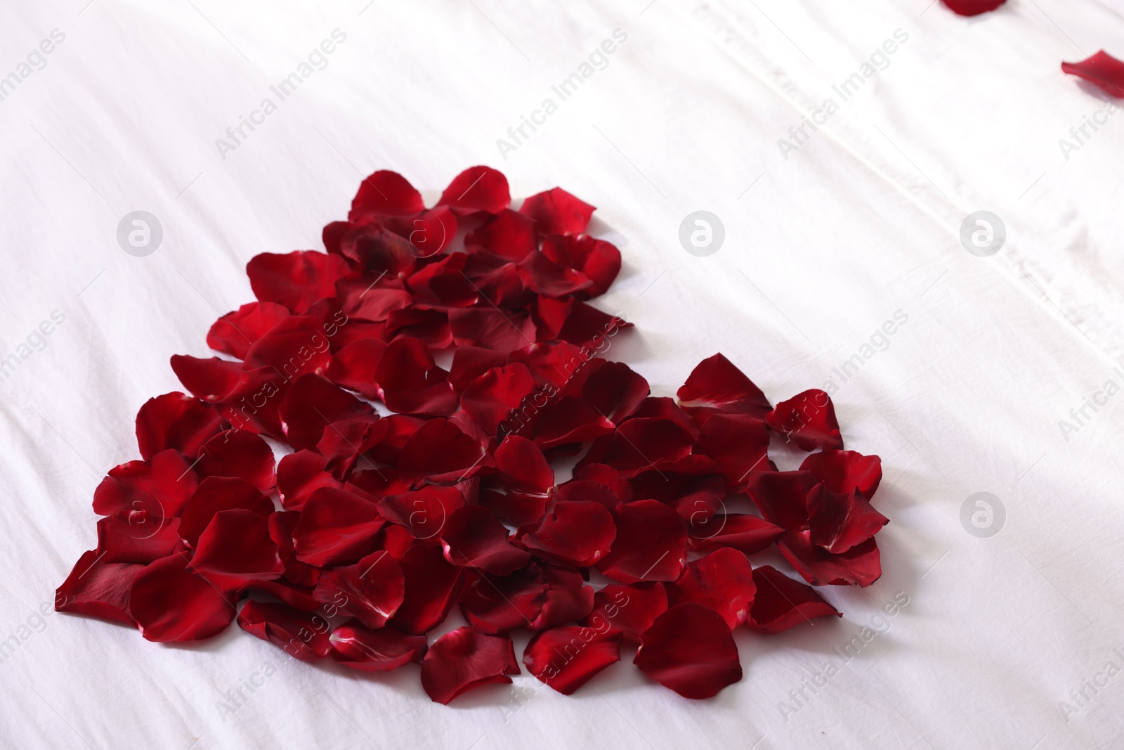 Photo of Heart made with beautiful rose petals on bed