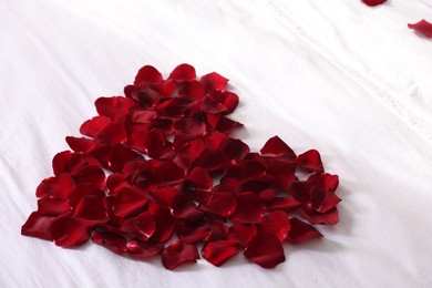 Photo of Heart made with beautiful rose petals on bed