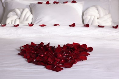 Photo of Heart made with beautiful rose petals on bed