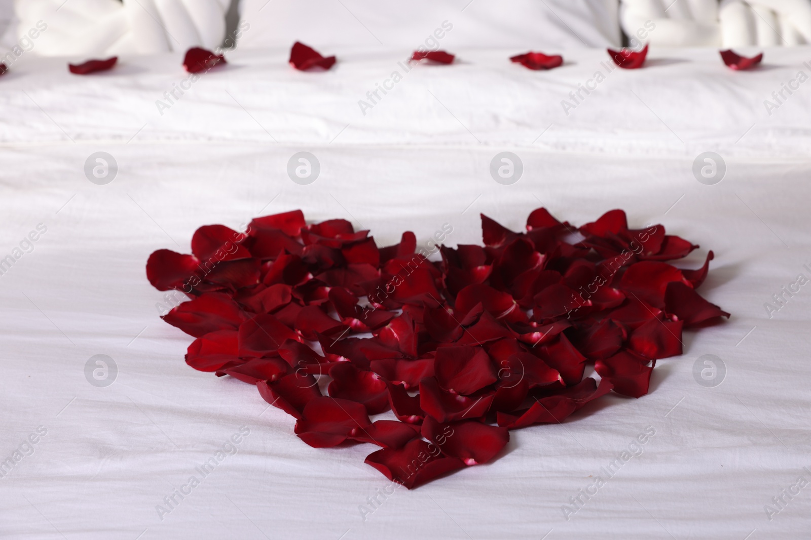 Photo of Heart made with beautiful rose petals on bed