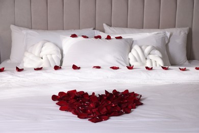 Photo of Heart made with beautiful rose petals on bed