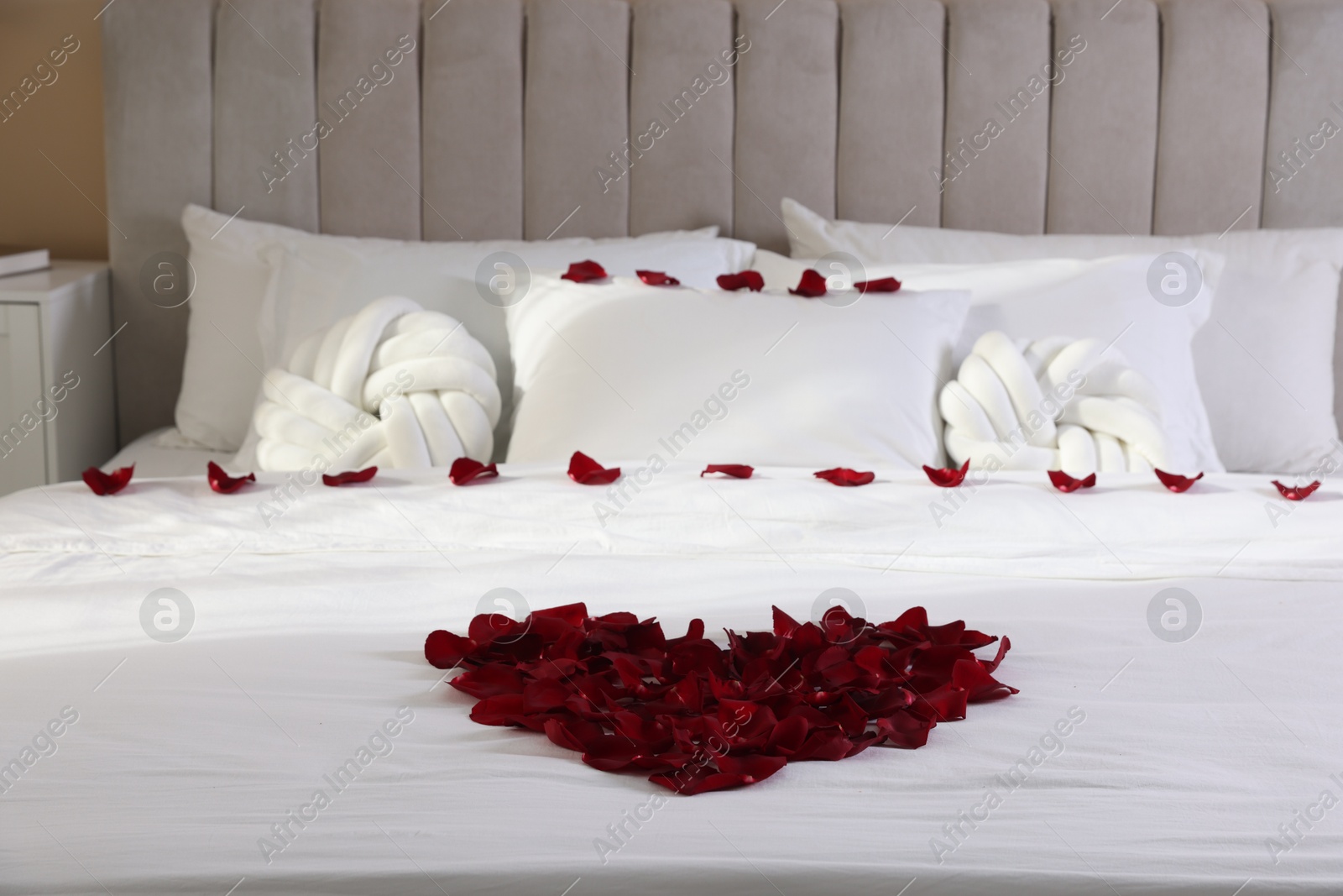 Heart made with beautiful rose petals on bed Photo of Heart made with beautiful rose petals on bed