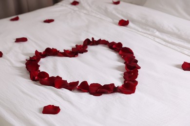 Photo of Heart made with beautiful rose petals on bed