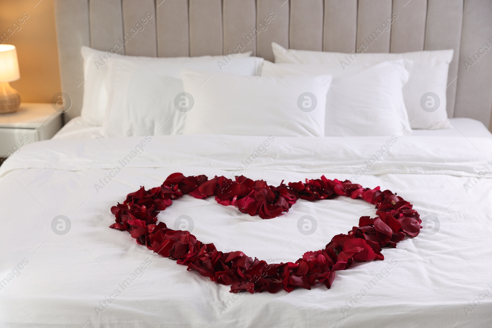 Photo of Heart made with beautiful rose petals on bed