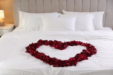 Photo of Heart made with beautiful rose petals on bed