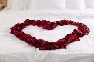 Photo of Heart made with beautiful rose petals on bed