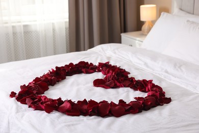 Photo of Heart made with beautiful rose petals on bed
