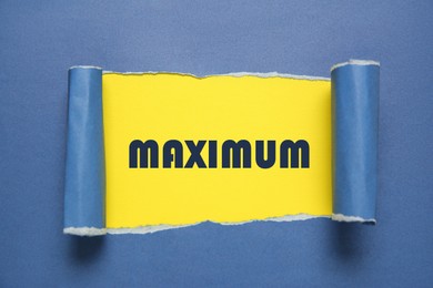 Image of Word Maximum on yellow background, view through hole in blue paper