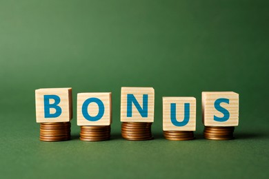 Image of Word Bonus made of cubes with letters on stacked coins against green background