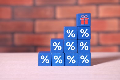 Image of Cube with gift box image on top of stacked ones with percent signs on table