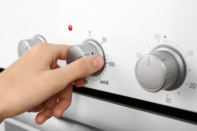 Image of Woman adjusting electric oven, closeup. Kitchen appliance