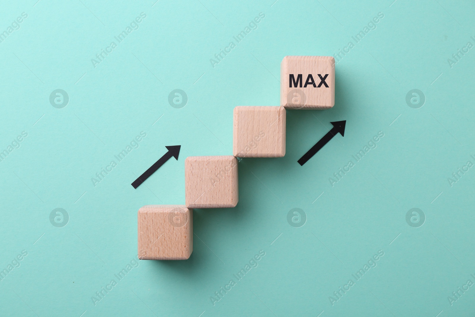 Image of One wooden cube with word Max among empty ones and arrows on turquoise background, top view