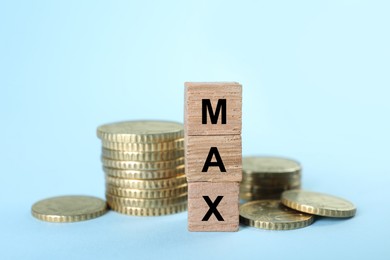 Image of Wooden cubes with word Max and coins on light blue background