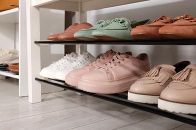 Photo of Stand with different stylish shoes indoors, closeup