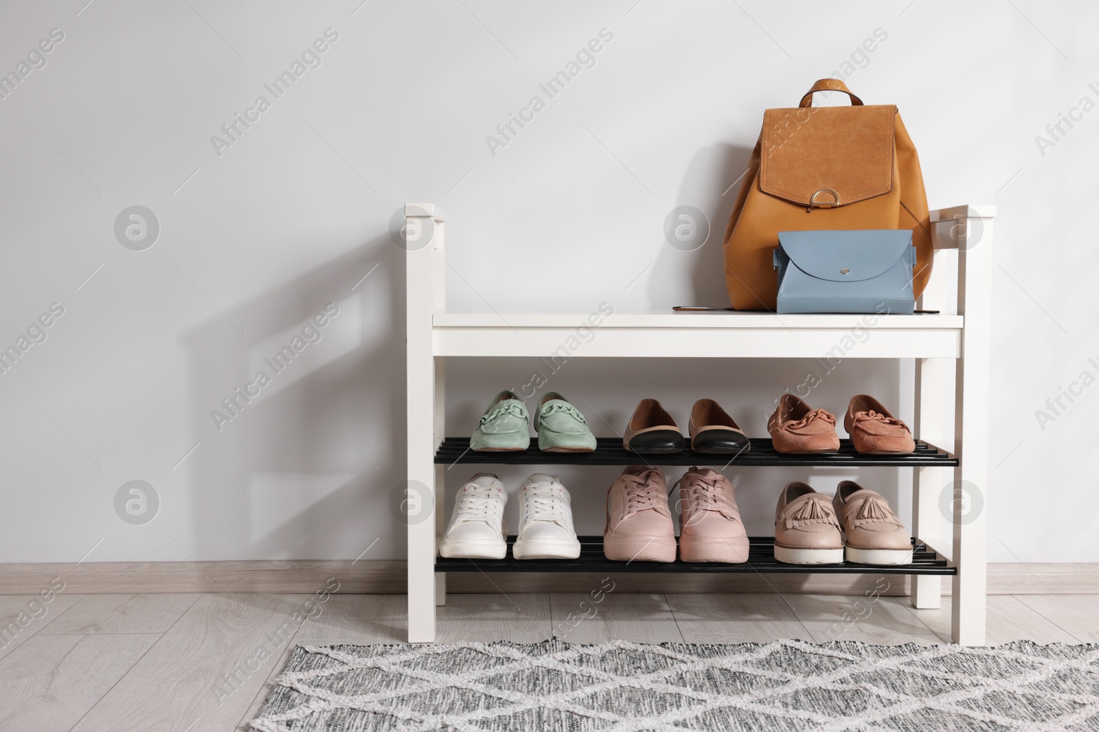 Stand with different stylish shoes and bags indoors. Space for text Photo of Stand with different stylish shoes and bags indoors. Space for text