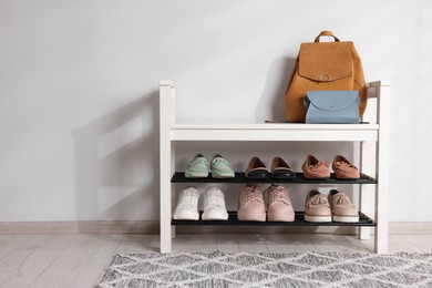 Photo of Stand with different stylish shoes and bags indoors. Space for text