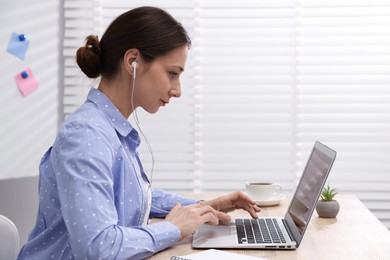 Photo of Online speaker streaming webinar with laptop at table indoors