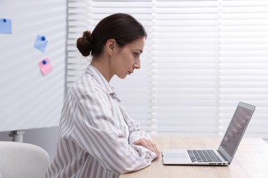 Photo of Online speaker streaming webinar with laptop at table indoors