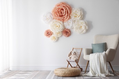 Photo of Beautiful decorative paper flowers on white wall in child's room