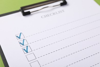 Photo of Checklist with marked checkboxes on green background, closeup