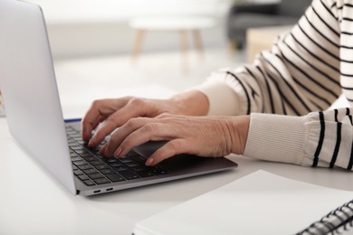 Photo of Woman learning online using laptop at white table indoors, closeup. Self-study