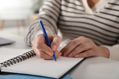 Photo of Woman taking notes at white table indoors, closeup. Self-study