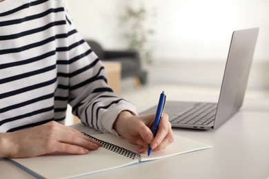 Photo of Woman taking notes at white table indoors, closeup. Self-study