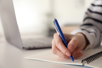 Photo of Woman taking notes at white table indoors, closeup. Self-study