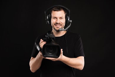 Photo of Man with professional video camera and headset on black background