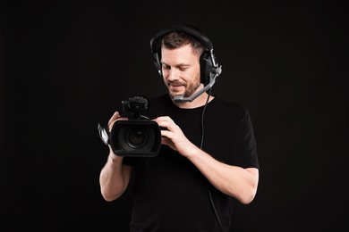 Photo of Man with professional video camera and headset on black background