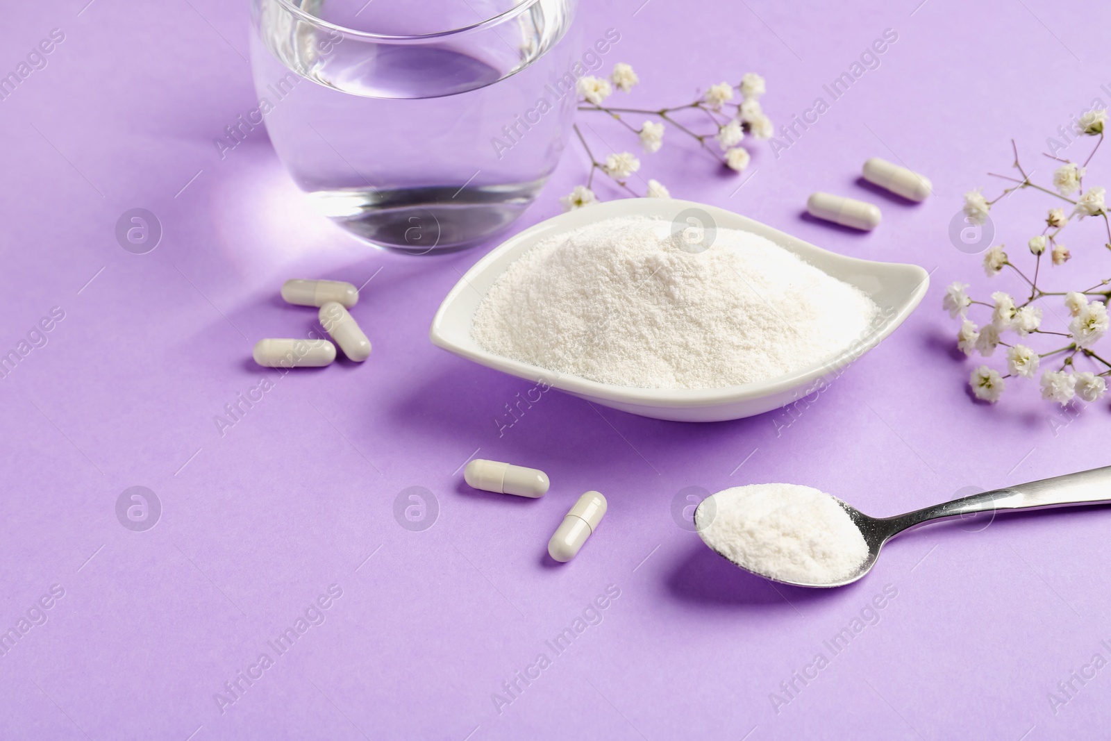 Collagen powder in bowl, spoon, pills, glass of water and gypsophila flowers on violet background Photo of Collagen powder in bowl, spoon, pills, glass of water and gypsophila flowers on violet background