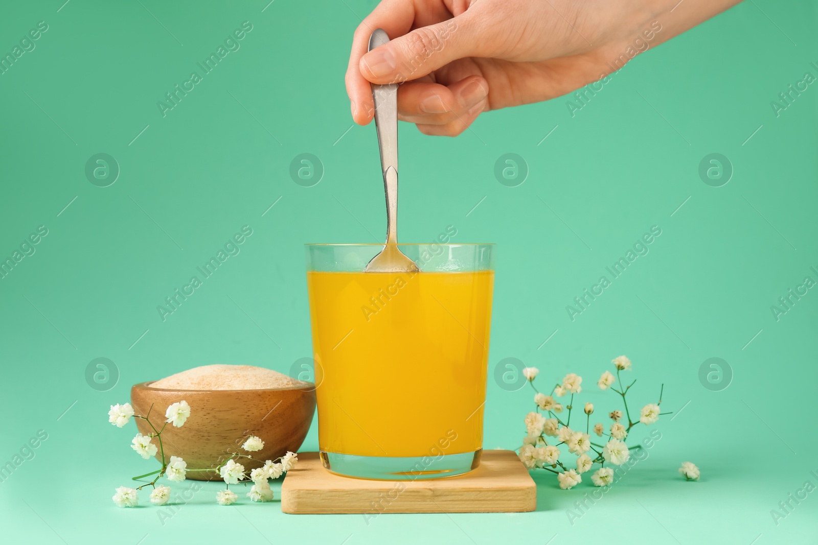 Woman stirring collagen powder in water on turquoise background, closeup Photo of Woman stirring collagen powder in water on turquoise background, closeup
