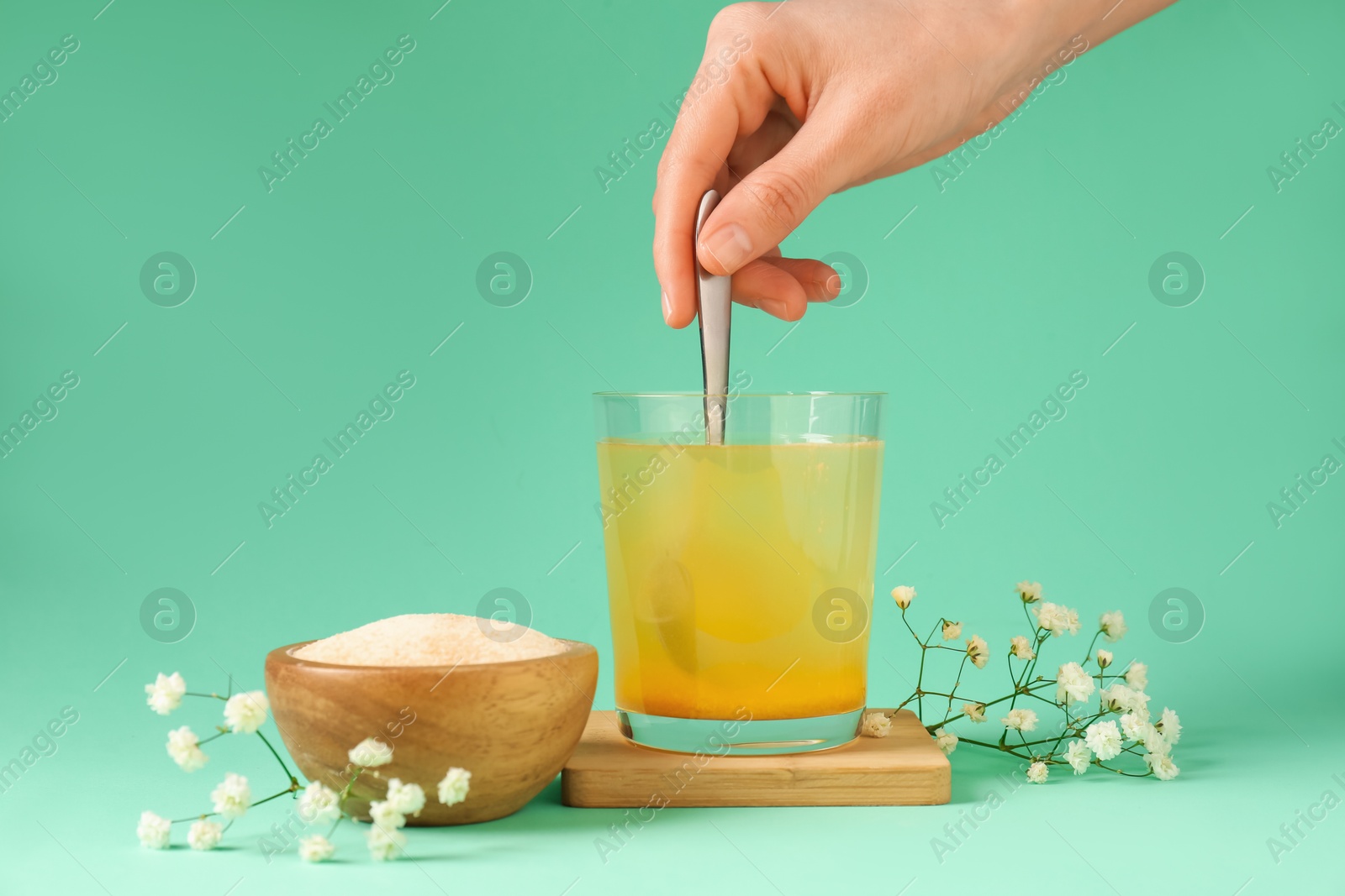 Woman stirring collagen powder in water on turquoise background, closeup Photo of Woman stirring collagen powder in water on turquoise background, closeup