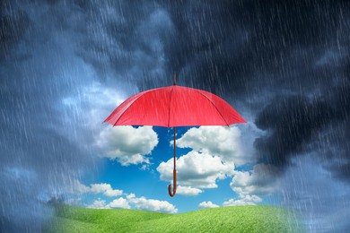 Image of Open red umbrella revealing green meadow under blue sky during heavy rainstorm