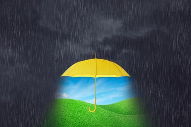 Image of Open yellow umbrella revealing green meadow under blue sky during heavy rainstorm