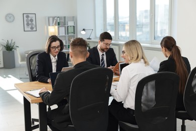 Photo of Coworkers working together at wooden table in office