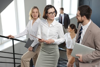 Photo of Group of coworkers walking up stairs indoors