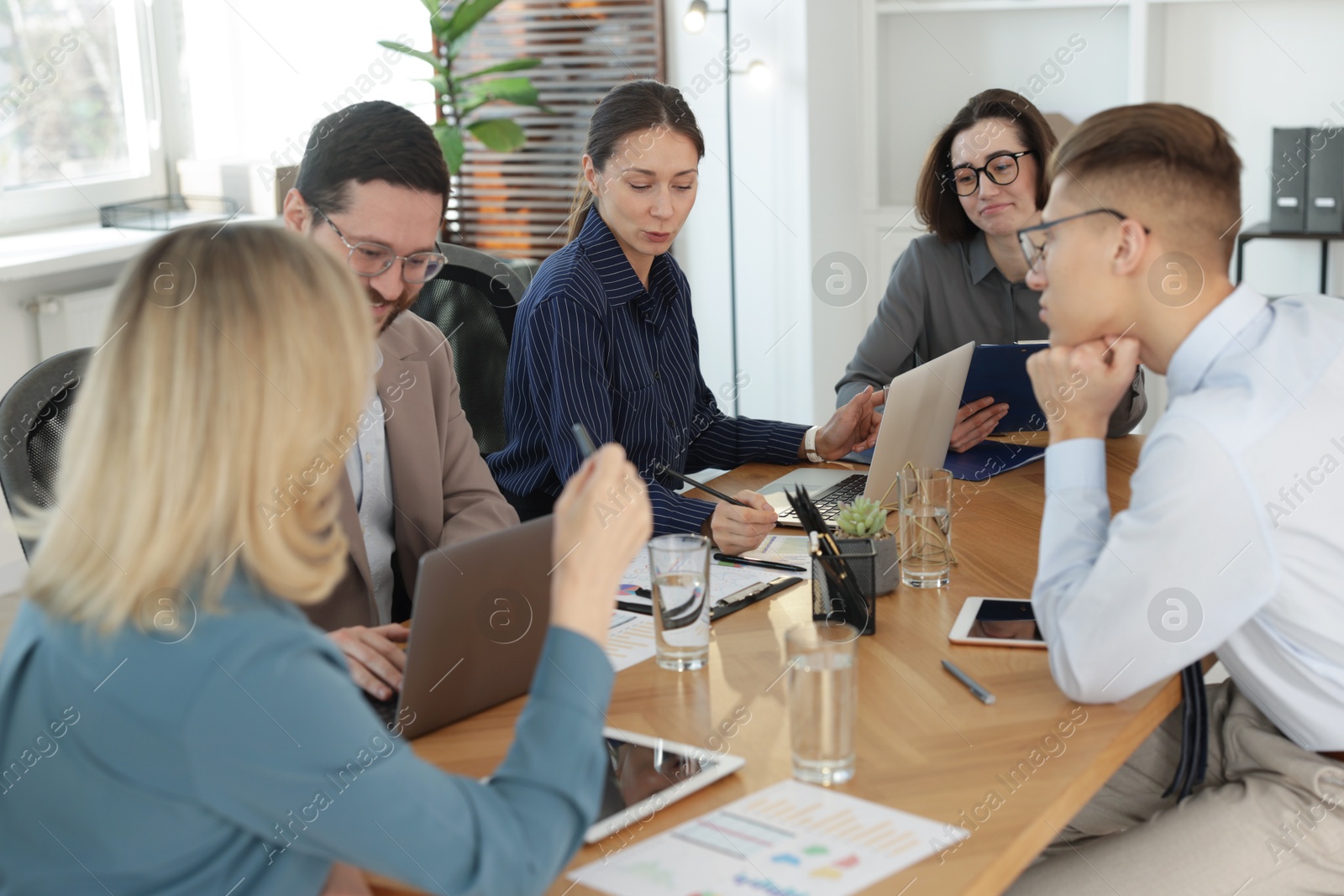 Photo of Coworkers working together at wooden table in office