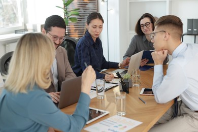 Photo of Coworkers working together at wooden table in office