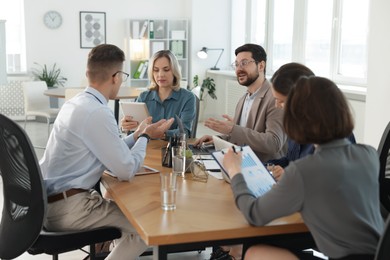 Photo of Coworkers working together at wooden table in office