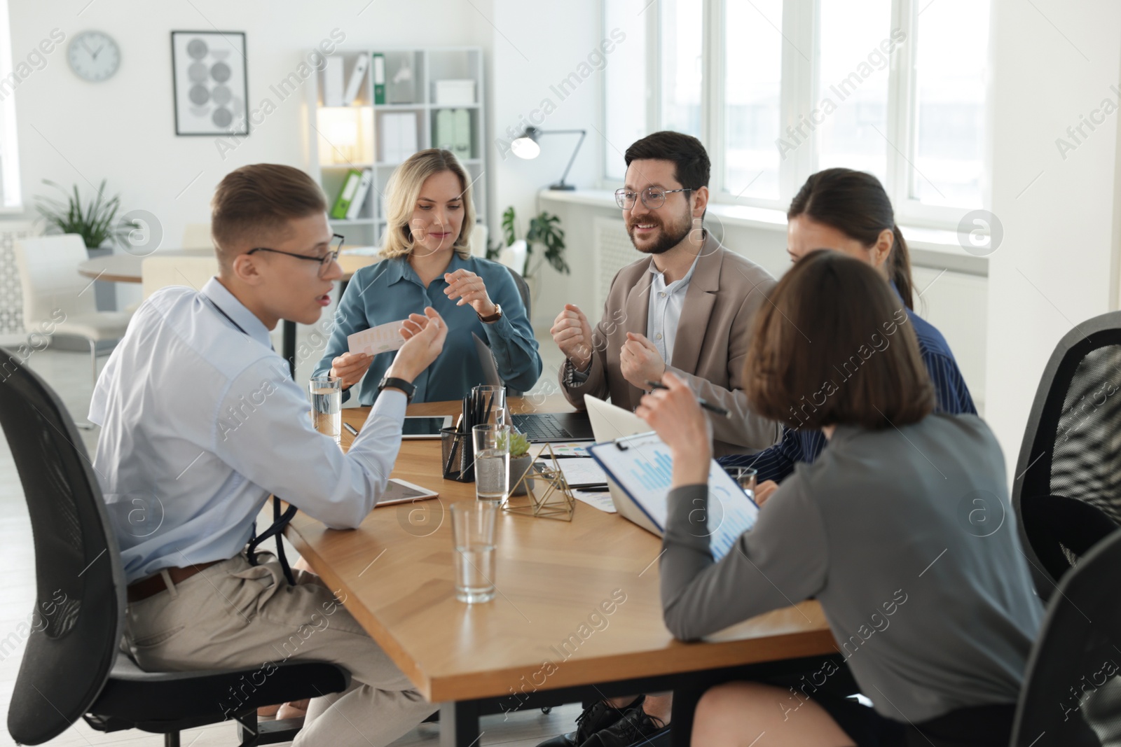 Photo of Coworkers working together at wooden table in office