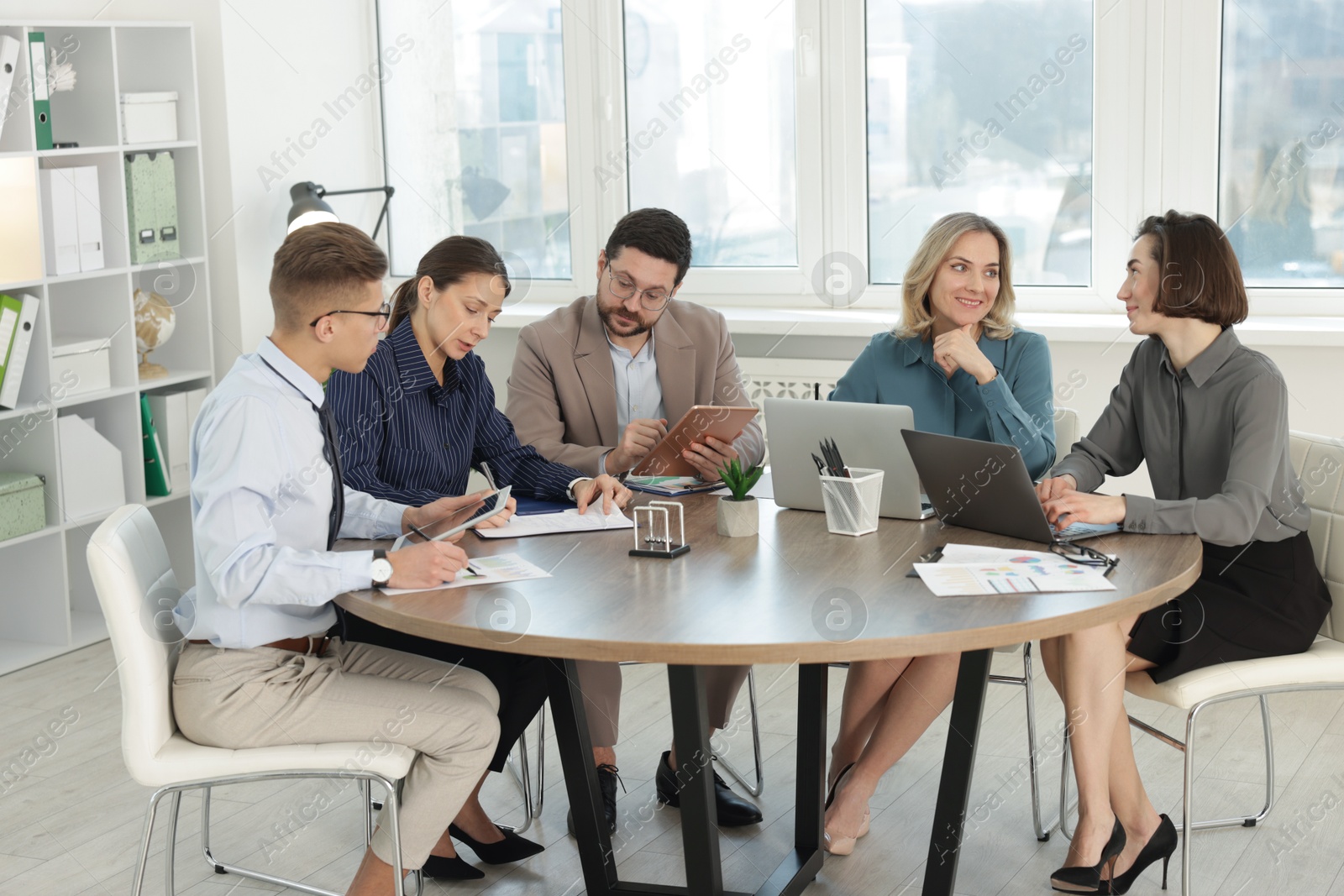 Photo of Coworkers working together at wooden table in office