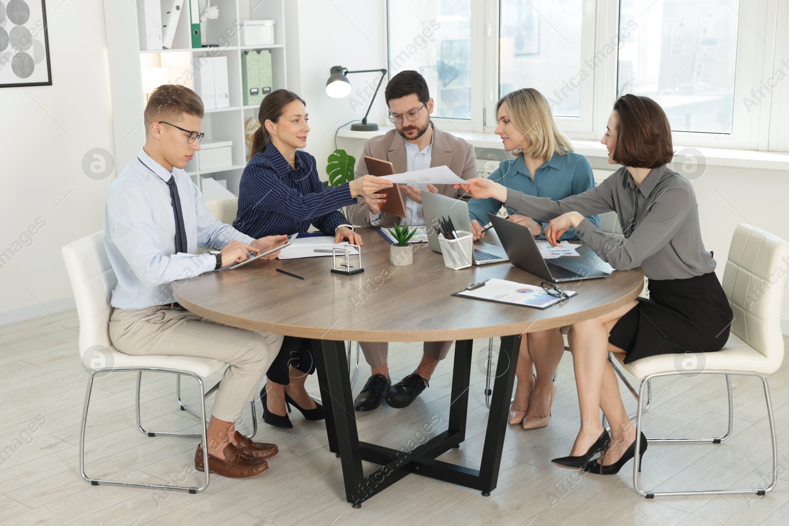 Photo of Coworkers working together at wooden table in office