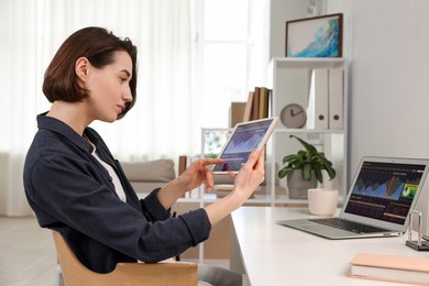 Photo of Stock exchange. Woman analysing financial market on tablet at white table indoors