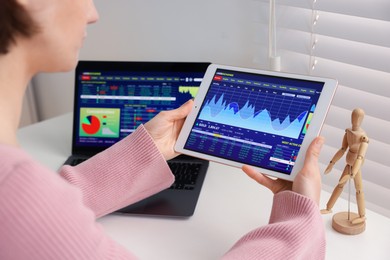 Photo of Stock exchange. Woman analysing financial market on tablet at white table indoors, closeup