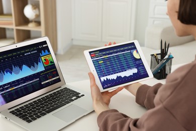 Photo of Stock exchange. Woman analysing financial market on tablet at white table indoors, closeup