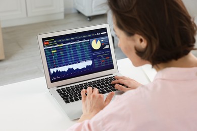 Photo of Stock exchange. Woman analysing financial market on laptop at white table indoors