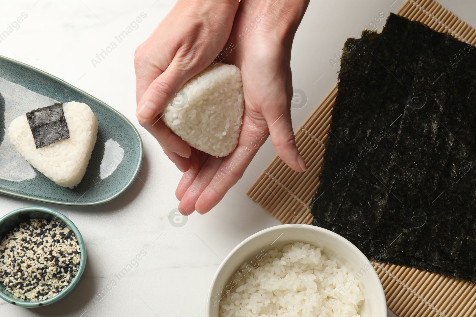 Woman making tasty onigiri (Japanese rice balls) at white table, top view Photo of Woman making tasty onigiri (Japanese rice balls) at white table, top view