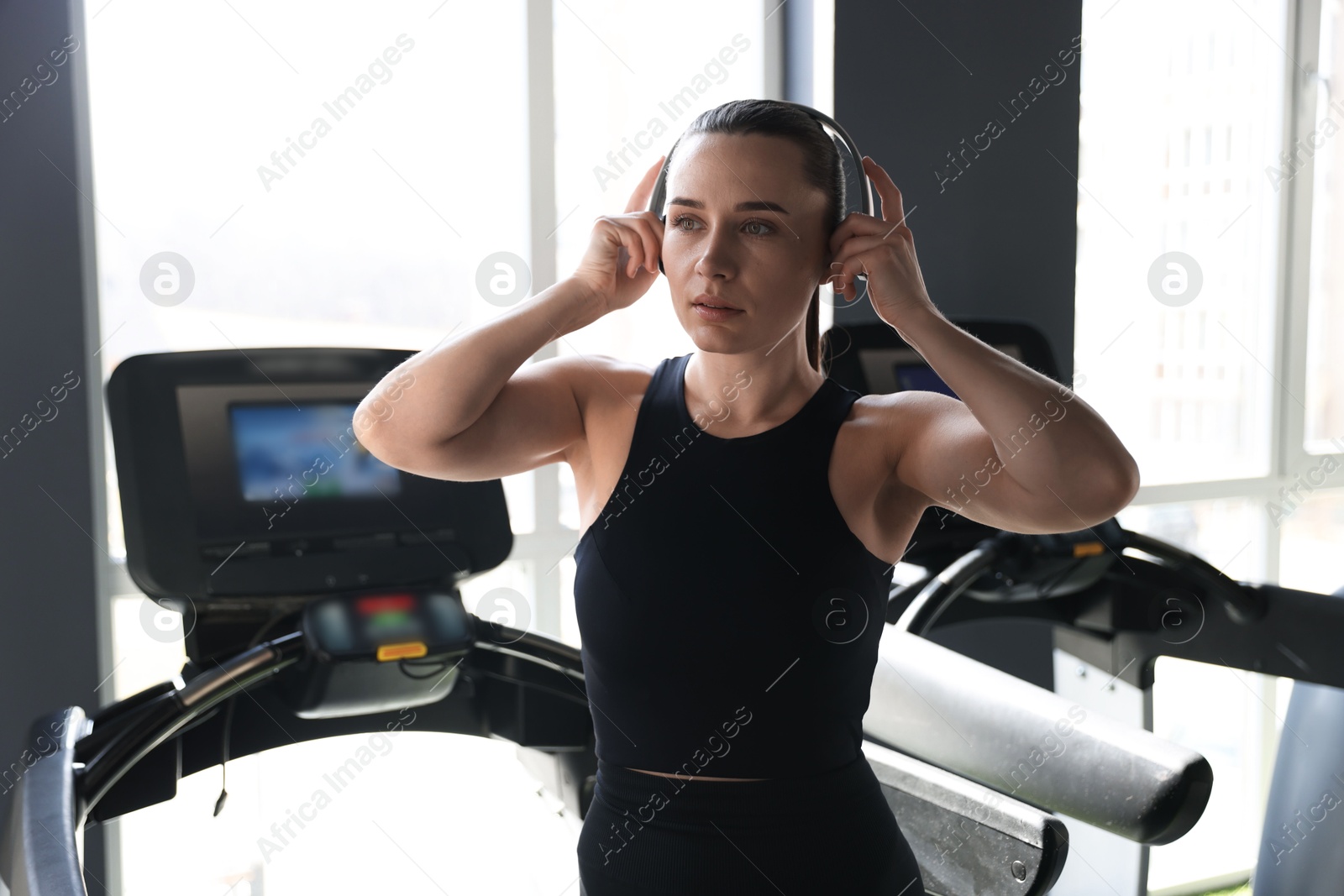 Photo of Athletic woman in headphones on treadmill in gym