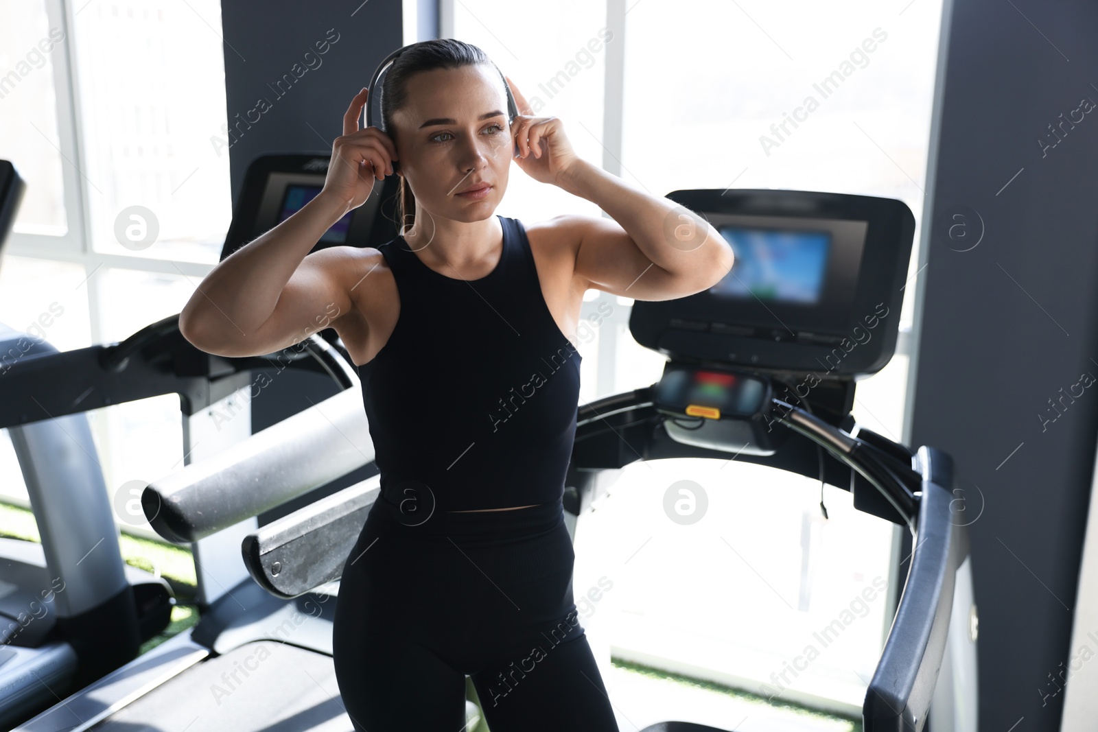 Photo of Athletic woman in headphones on treadmill in gym